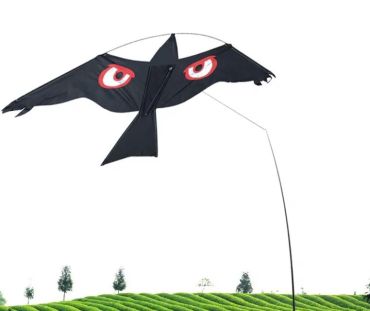 Sort skræmmefugl på stang i luften over en mark